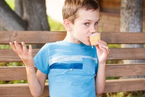 junge mit blauem t-shirt bekleckert sich mit eis