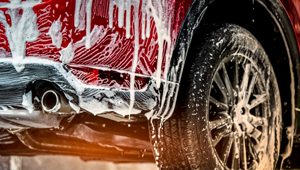 rotes Auto ist mit Autoshampoo eingeschäumt