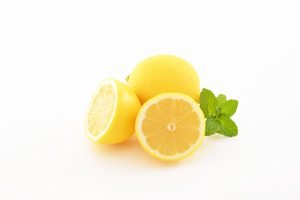 eine ganze und zwei halbe Zitronen auf weißem Grund
