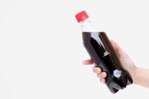 Hand hält Flasche Cola vor weißem Hintergrund