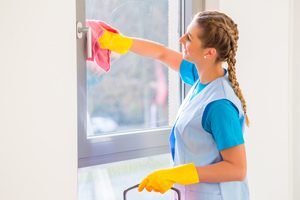 Frau putzt Fenster mit rosa Lappen