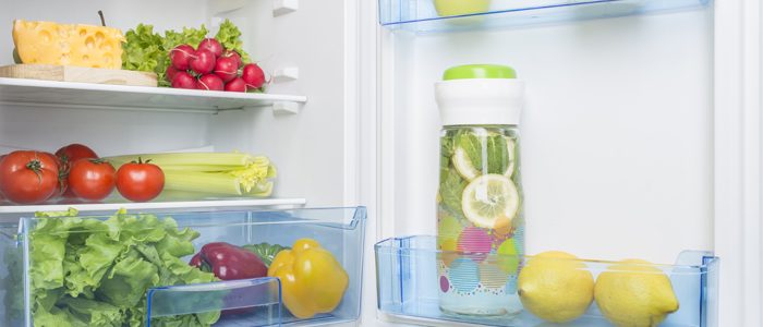 offener, sauberer Kühlschrank mit Gemüse und Zitronenwasser