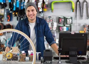 junger Mann hinter des Kasse eines Fahrradfachhandels