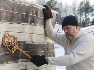 Mann mit Teppichklopfer und Teppich