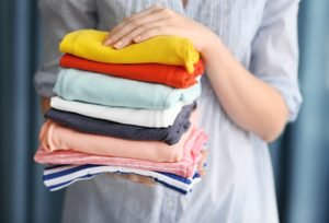 Frau hält einen Stapel gefalteter Wäsche