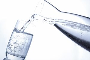 Wasser wird aus einer Karaffe in ein Glas gegossen