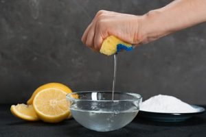 Zitronen neben Wasserschüssel mit Hand und Schwamm