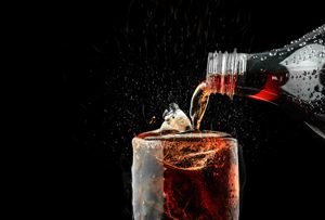 Cola wird aus Flasche in Glas gegossen