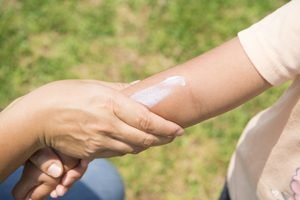 Hand reibt Kinderarm mit Sonnencreme ein