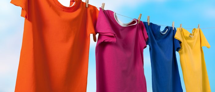 bunte Shirts hängen auf einer Leine vor blauem Himmel