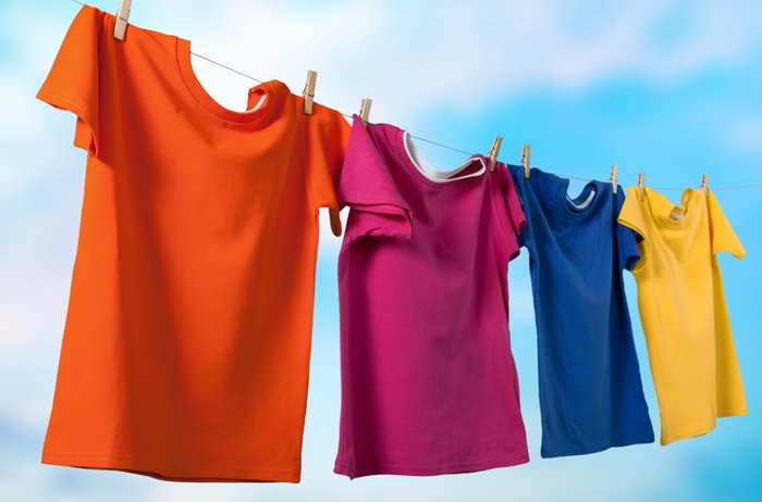 bunte Shirts hängen auf einer Leine vor blauem Himmel