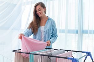 Frau hängt Wäschestücke auf Wäscheständer